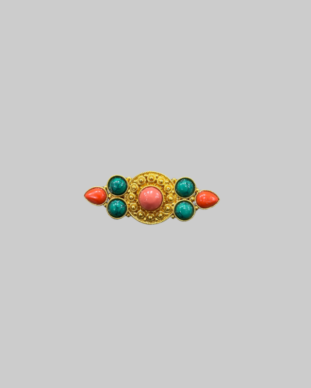 Vintage gold-toned brooch featuring red and green cabochon stones.